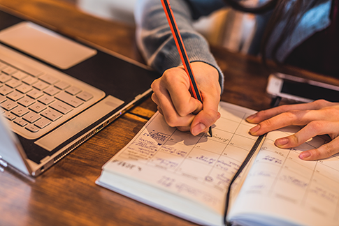 Photo of a person jotting down an appointment in a calendar book